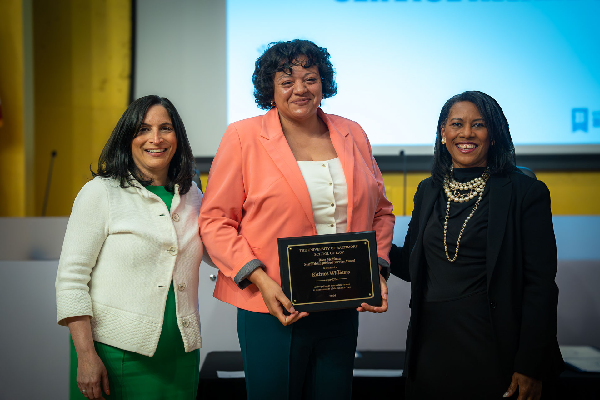 Three people pose during a University of Baltimore School of Law awards ceremony, with one recipient holding an award plaque.