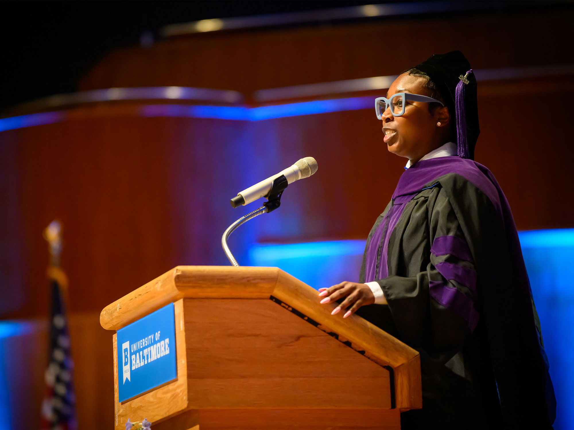 Krystle Sanders speaks at a University of Baltimore podium during a law school commencement ceremony.