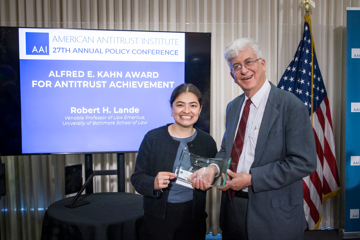 Robert H. Lande and a UBalt Law Student smile while holding the Alfred E. Kahn Award for Antitrust Achievement at the American Antitrust Institute’s 27th Annual Policy Conference.