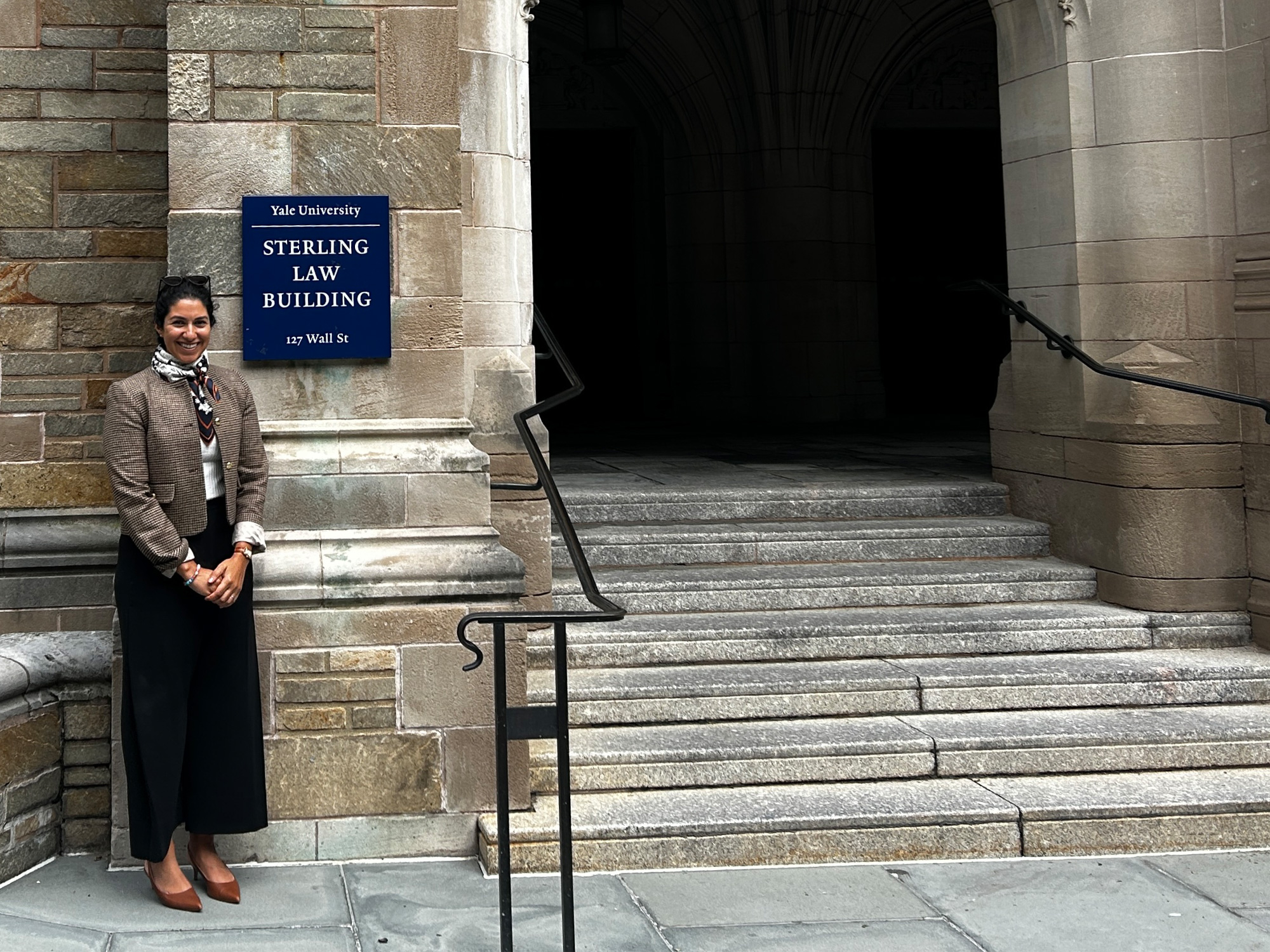 Professor Zina Makar stands beside the entrance to Yale University’s Sterling Law Building