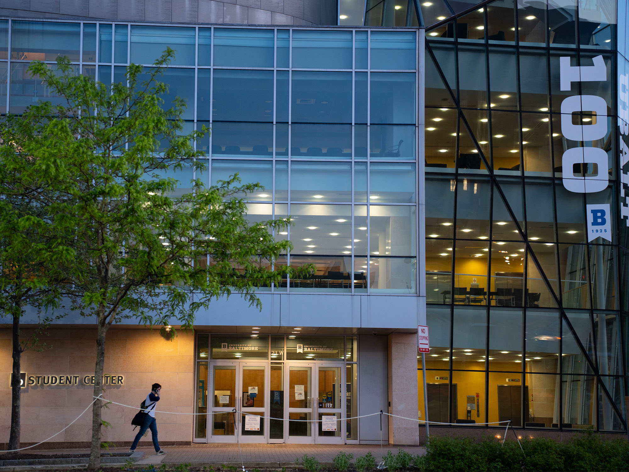 A student walks toward the door of the Student Center at dusk. 