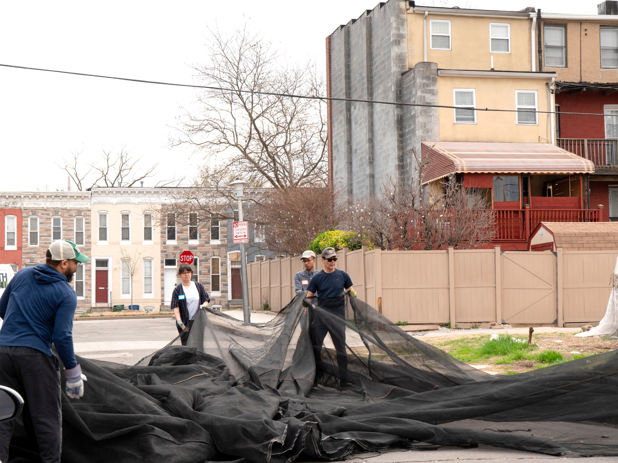 Volunteers grab pieces of a cover for greenhouses that will shield them from too much sunlight.