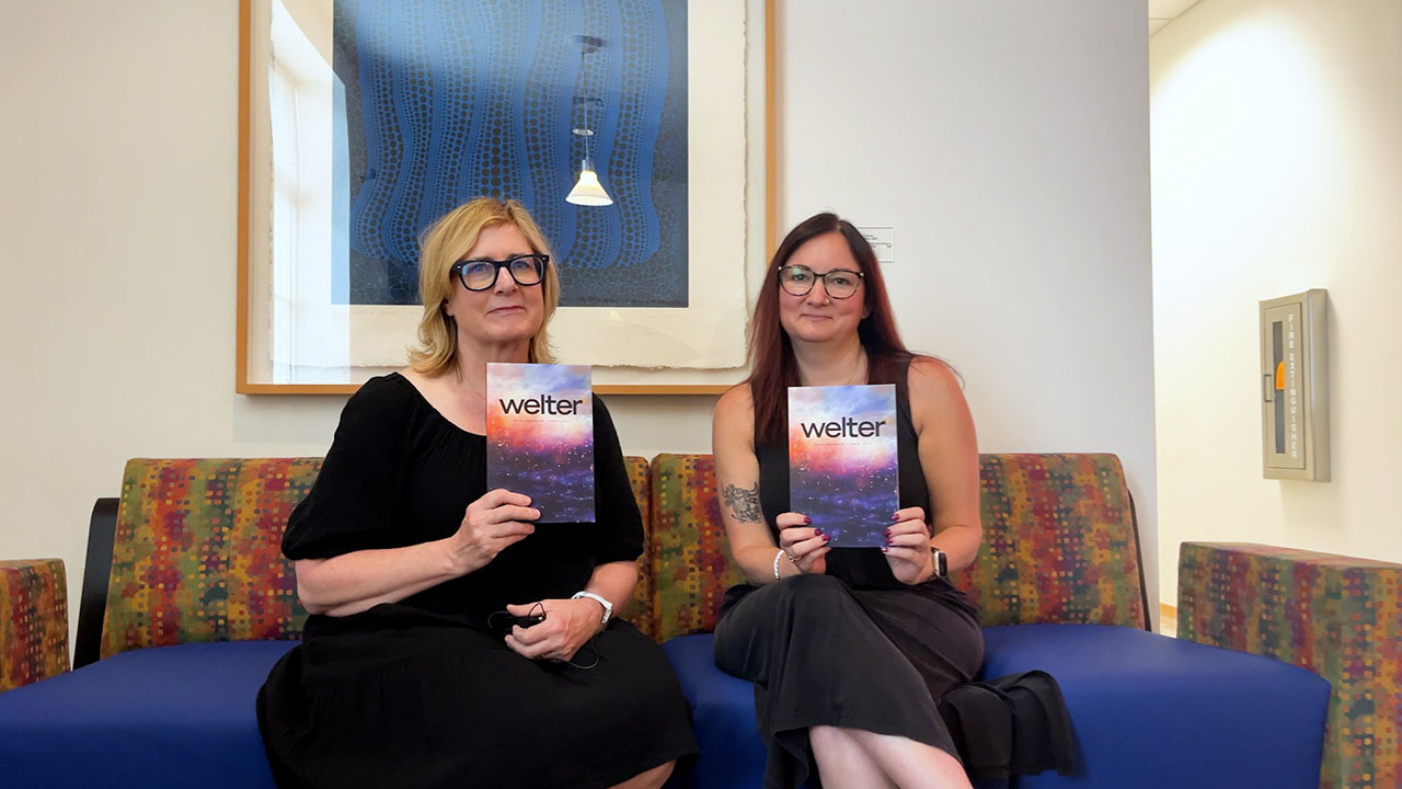 Two students hold up books they edited