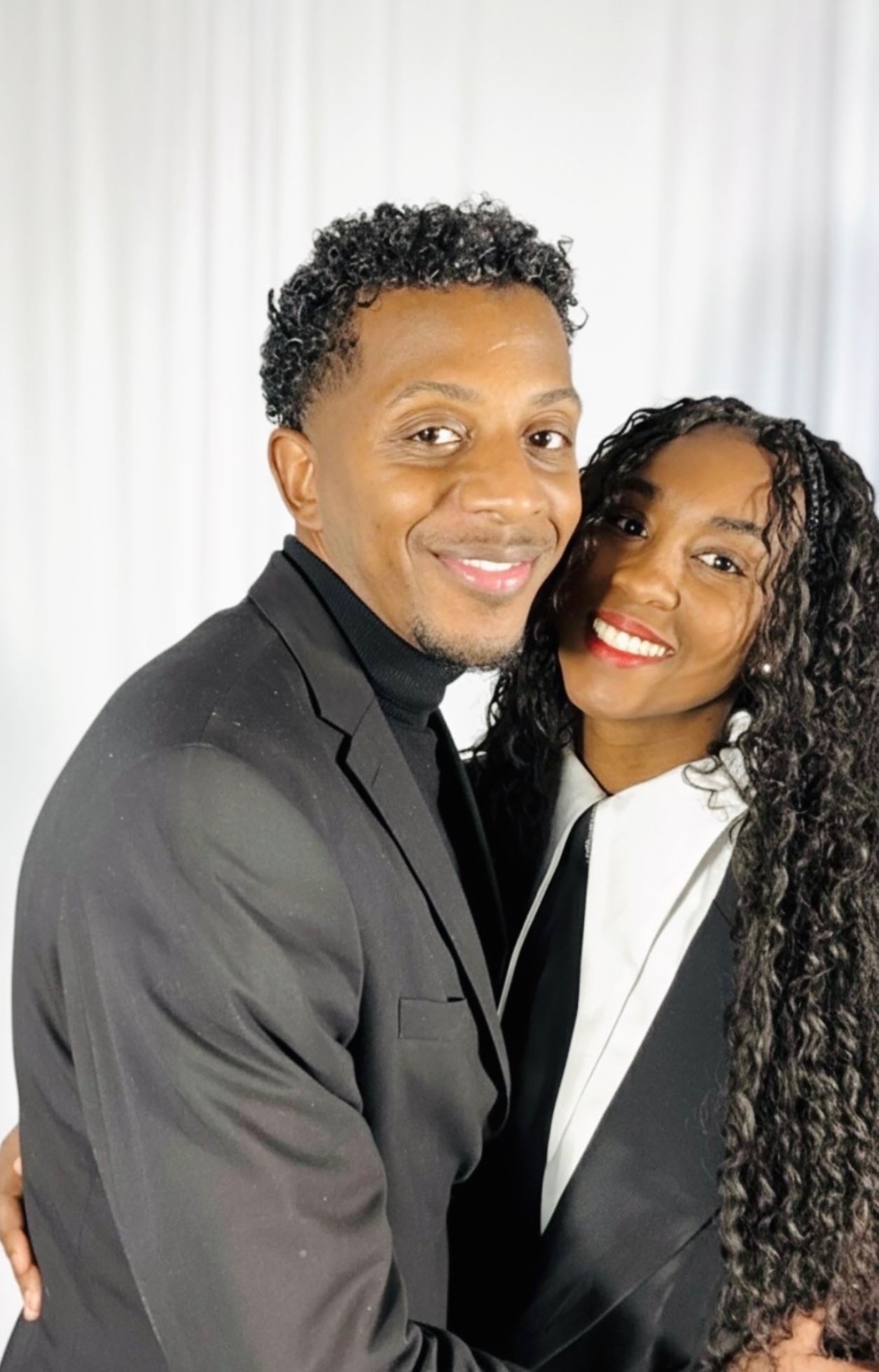 Justin and Natrea Wills, dressed formally, pose for a photo. 