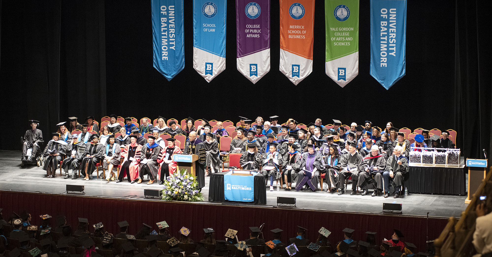 Image of the UBalt Commencement Ceremony featuring a stage full of faculty