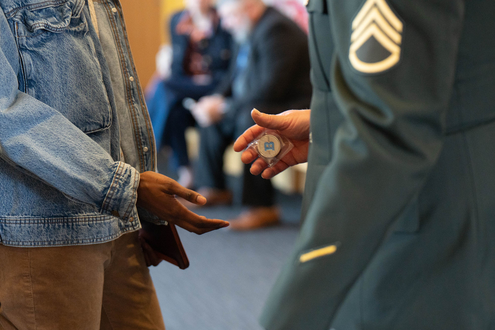 One person shaking hands with a veteran/military personnel