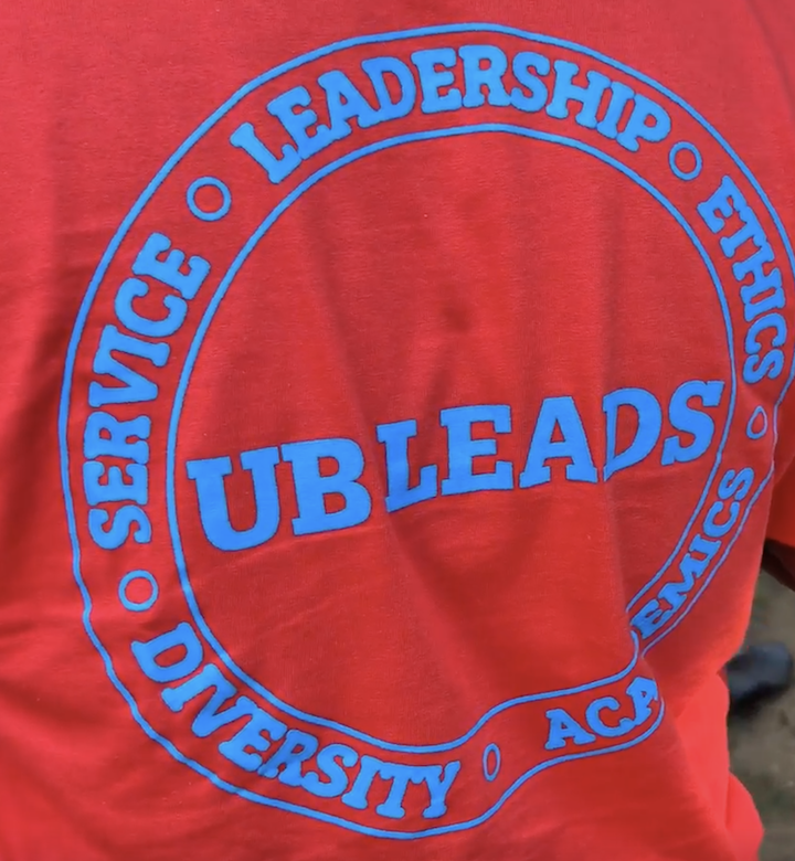 Blue circular UBLeads logo embroidered on red fabric, surrounded by the words “Service, Leadership, Diversity, and Integrity.”