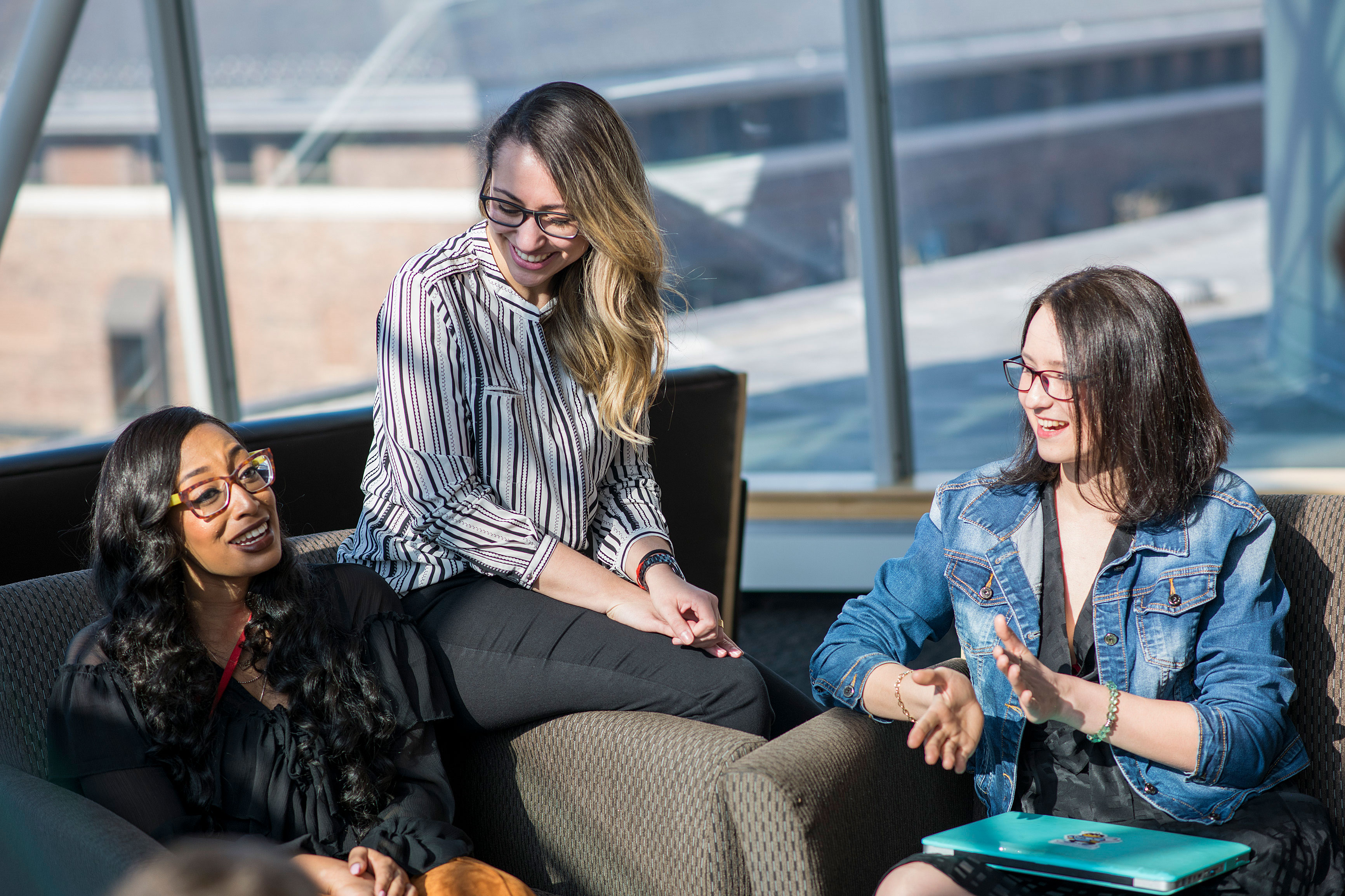 Three women converse while seated together in a law school lounge.