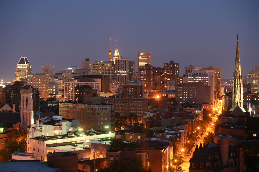 Baltimore’s downtown skyline illuminated at night, with city streets and buildings in the foreground.