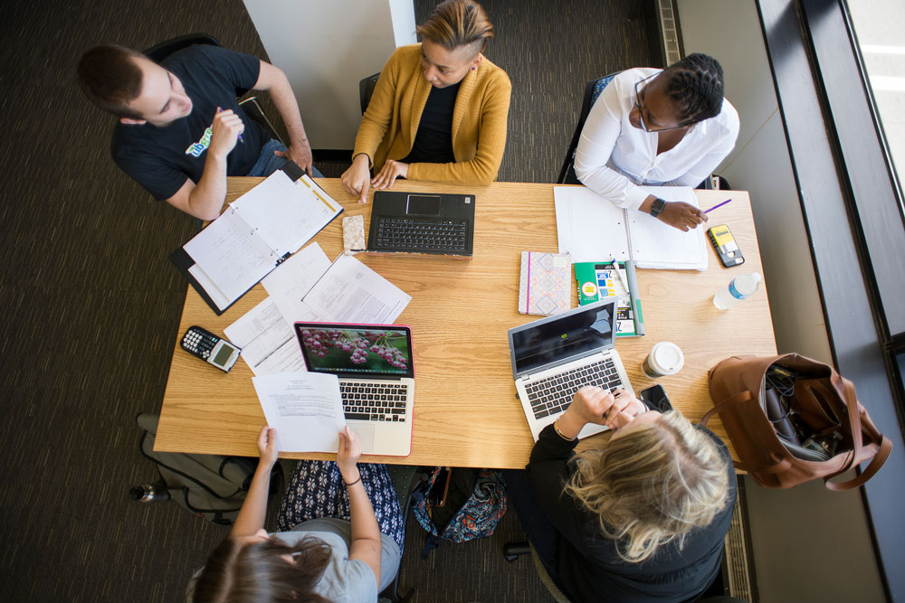 Law students collaborate around a table, reviewing notes and discussing coursework during a study session.