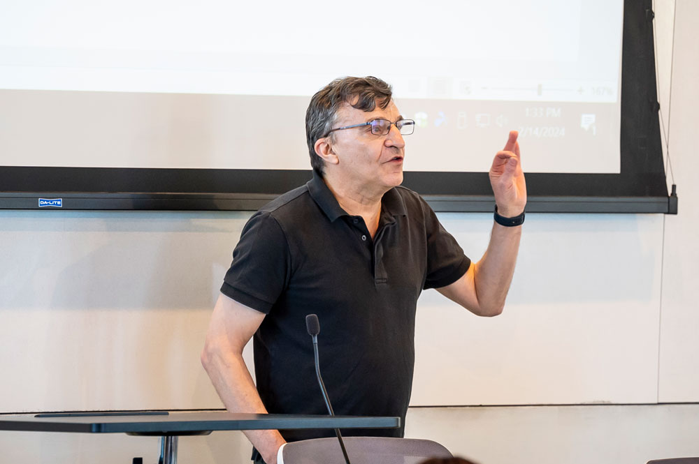 A professor gestures while speaking at the front of a law school classroom.