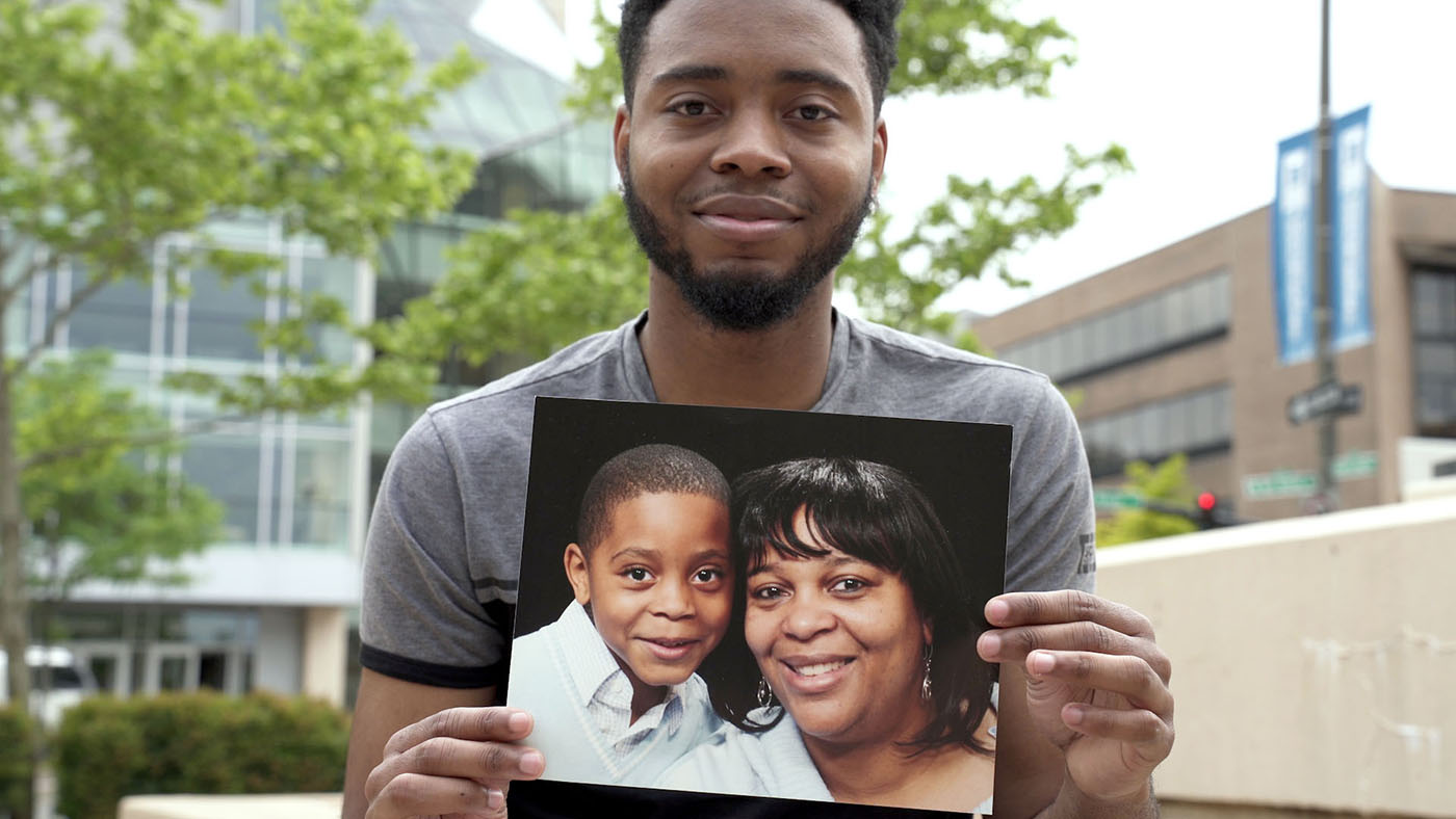 Demetrius holds a picture of himself at a younger age with his mom 