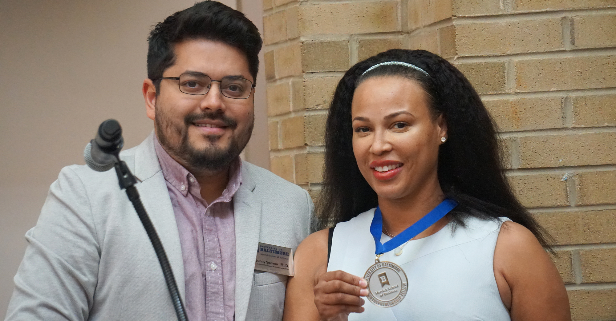 Dr. Sanwar Sunny present the Ratcliffe Entrepreneurship Fellows Medallion to Aasha Mikha’El.
