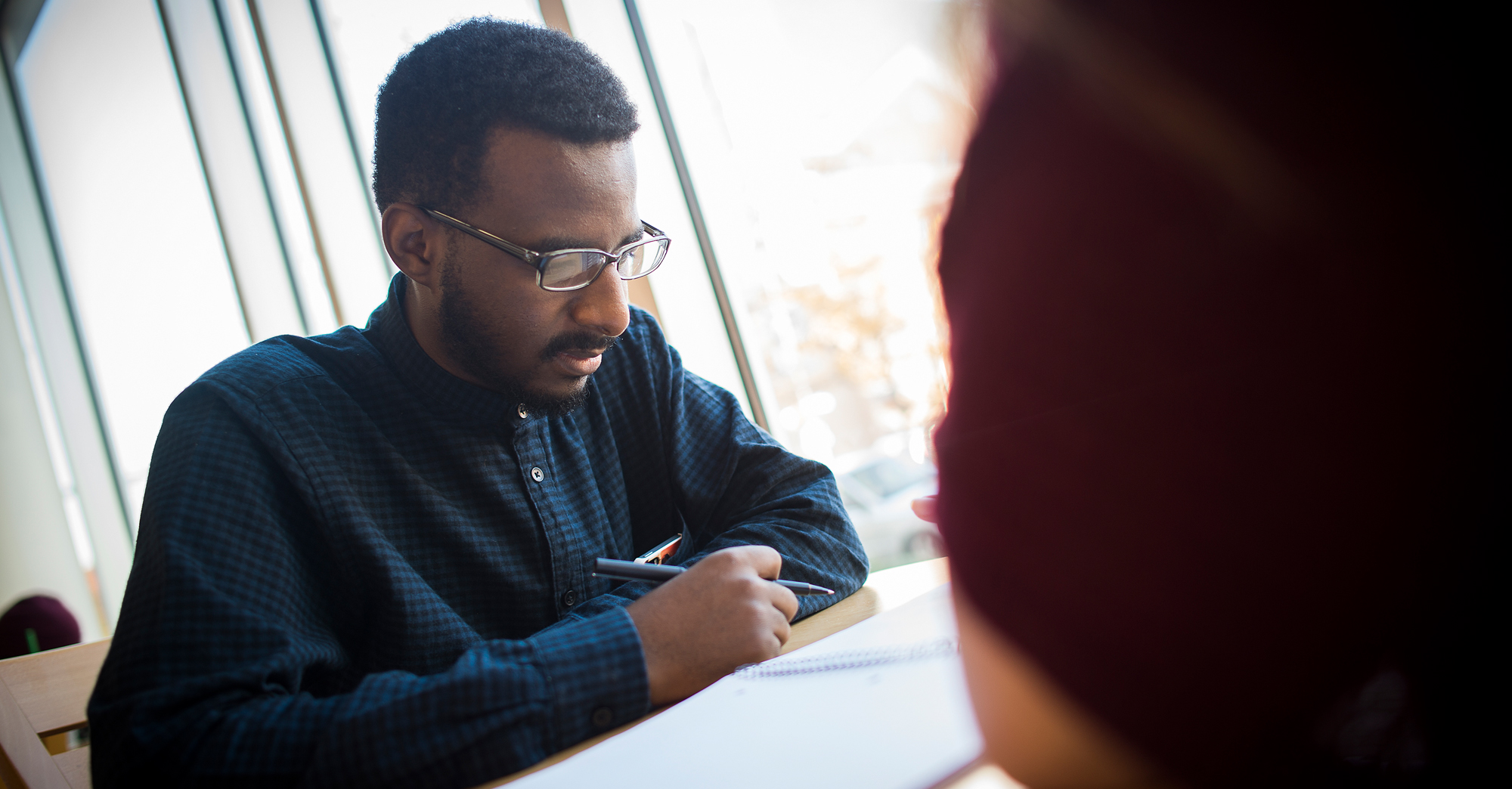 male writing in a notebook in the student center