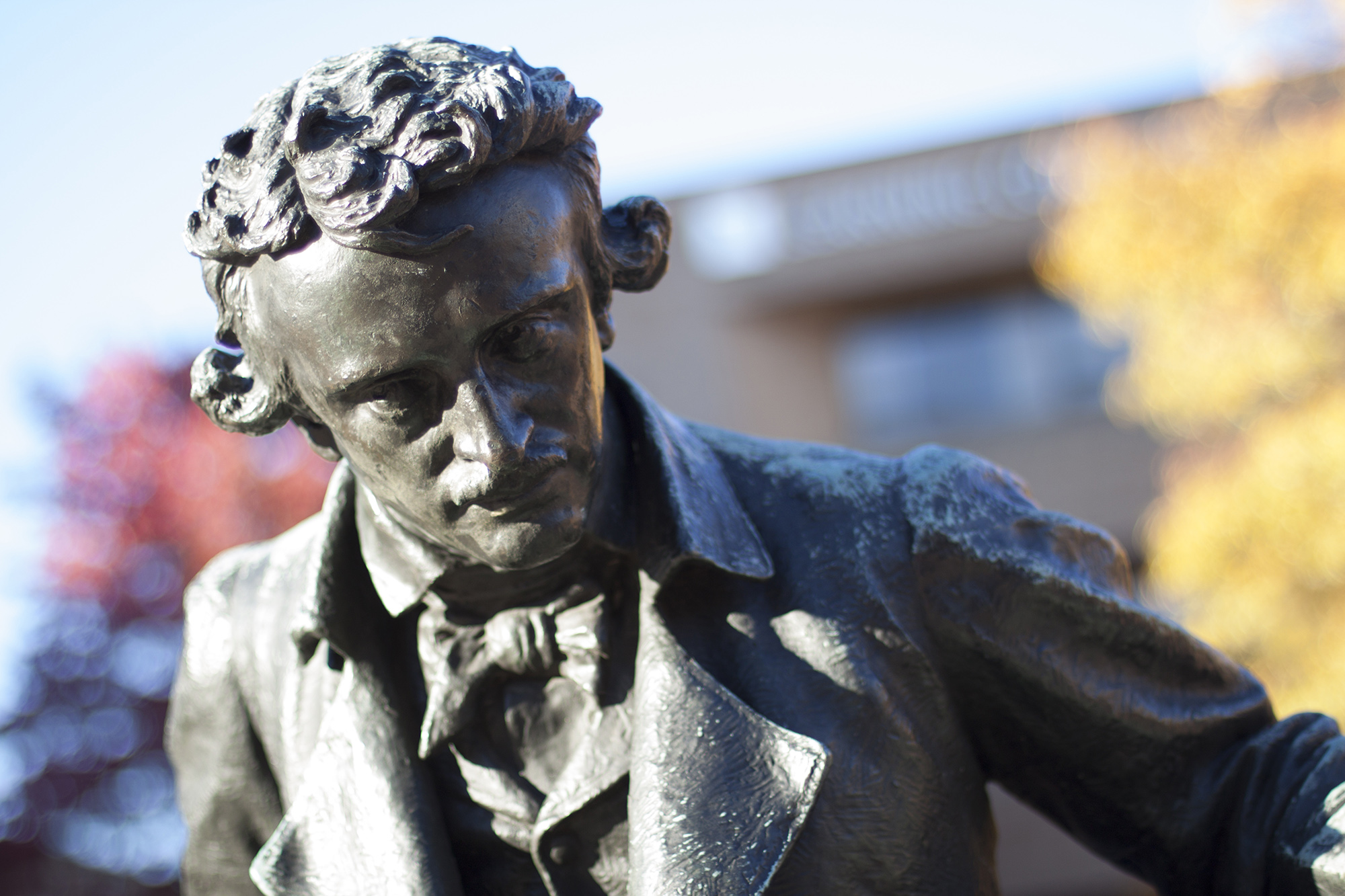 Edgar Allen Poe Statue with autumn leaves in the background on the UBalt campus