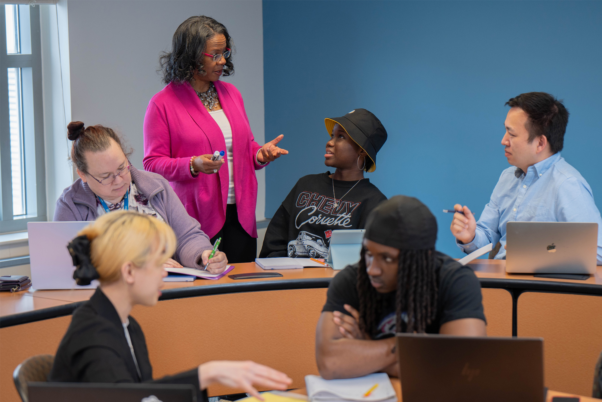Five business students in a classroom with a professor.