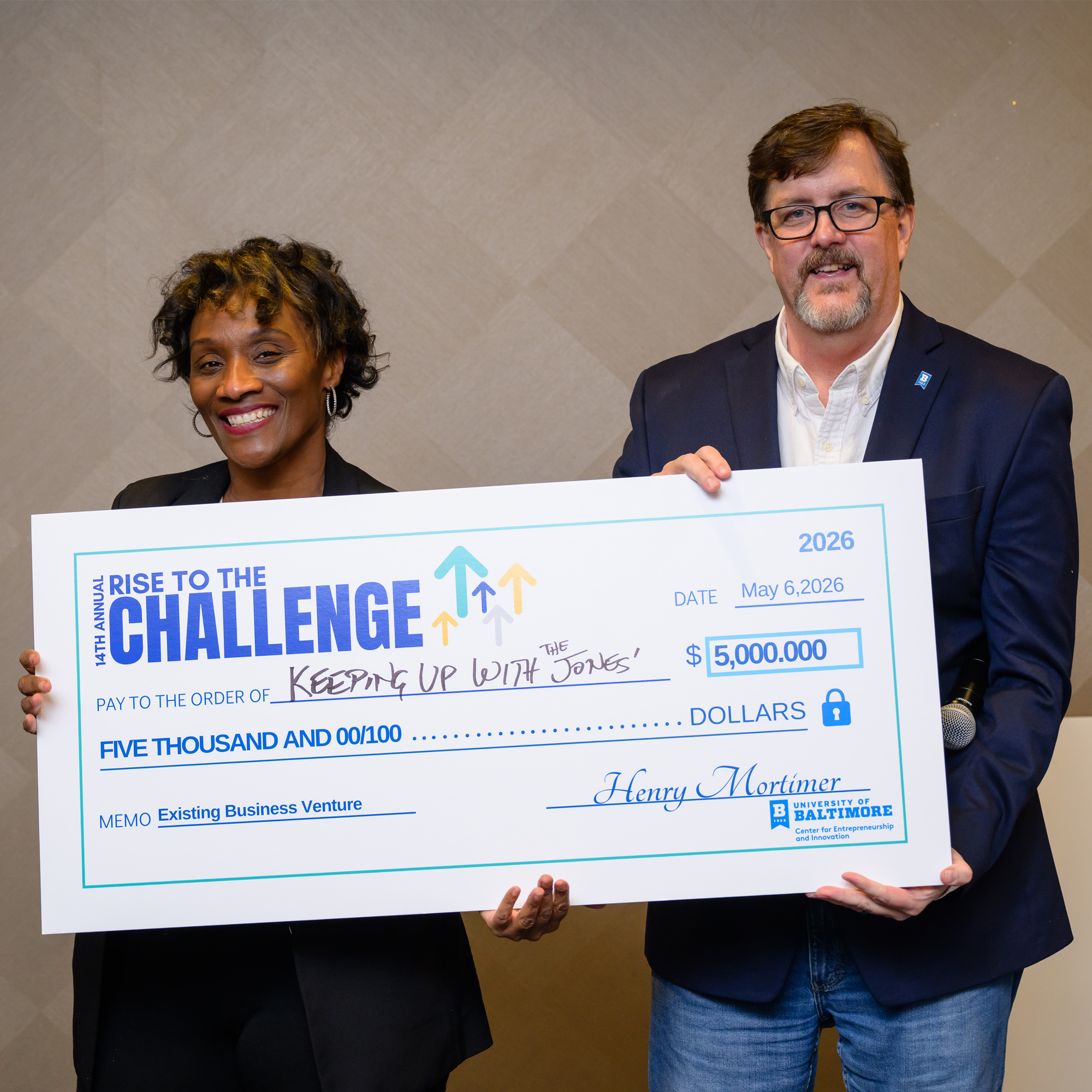 Hope Jones and Henry Mortimer pose with the Rise to the Challenge oversized check