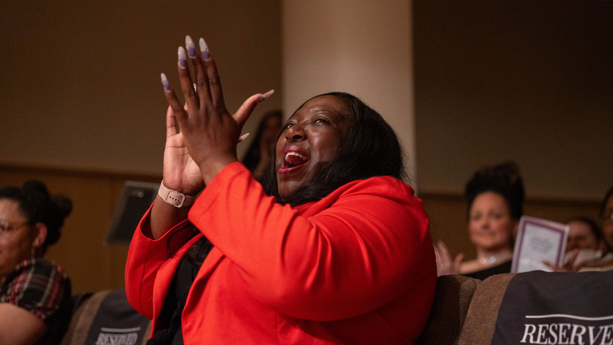 an audience member stands to applaud with a big smile