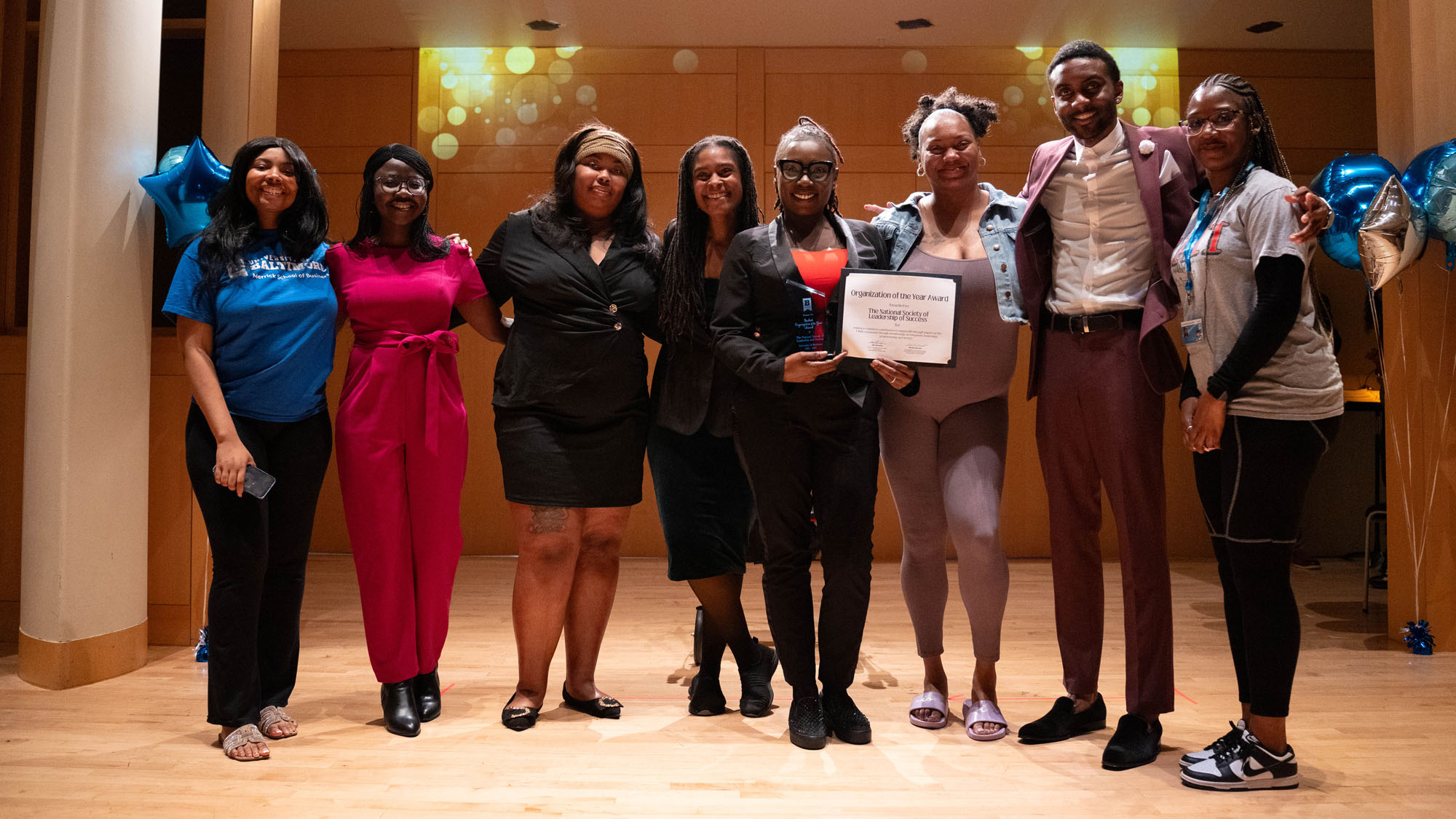 A large group of students from a winning organization pose together on a stage