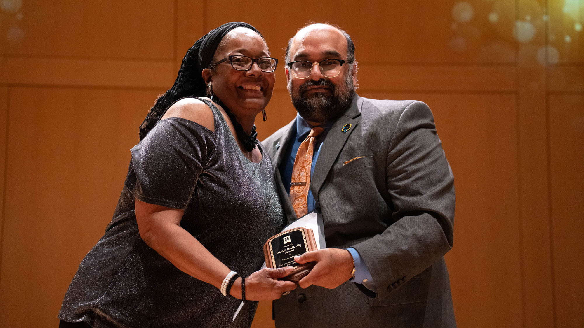 An event winner poses with the presenter while each hold the award